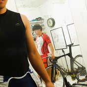 まぼろし工房内の写真。競輪選手二人と競技用自転車が写っている。もともとはプロスピードスケートや競輪競技用として開発。リンク先には、三本ローラーでロードバイクを乗っているときのテスト動画と、時速70キロ速度でも、ラクちんソックスは体のブレを抑えているグラフが掲載されている