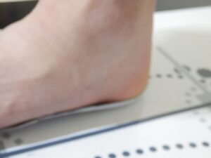 靴から取り外した中敷きに踵を合わせ、足幅、小指の位置、足跡の左右差を確認している様子